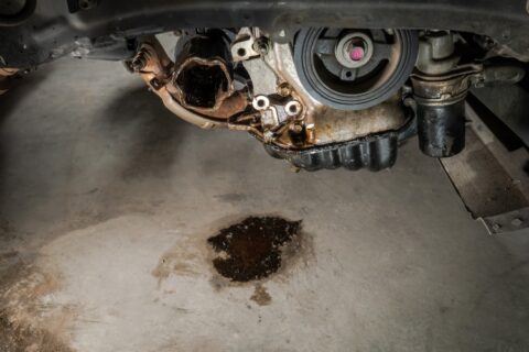 Transmission fluid leak beneath vehicle drivetrain causing oil puddle on floor