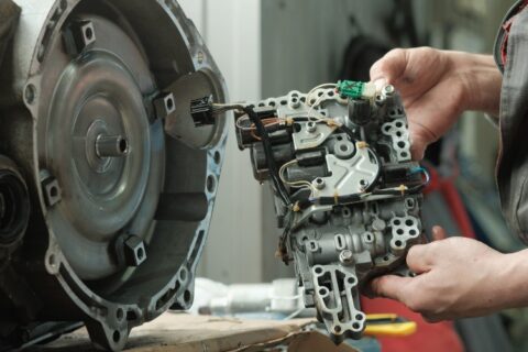 Technician replacing automatic transmission valve body inside transmission housing